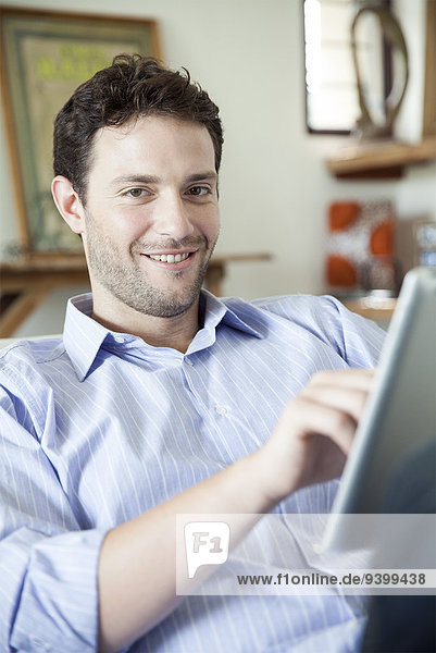 Man using digital tablet  smiling at camera