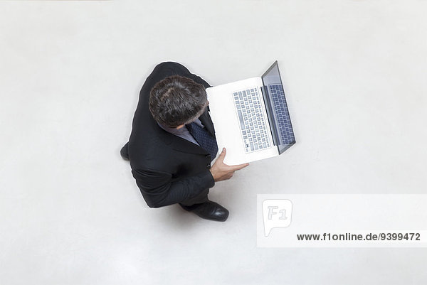 Businessman standing in lobby  using laptop computer