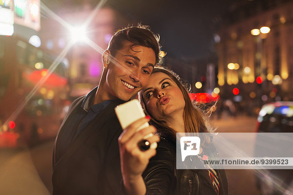 Paar fotografiert zusammen mit dem Handy bei Nacht