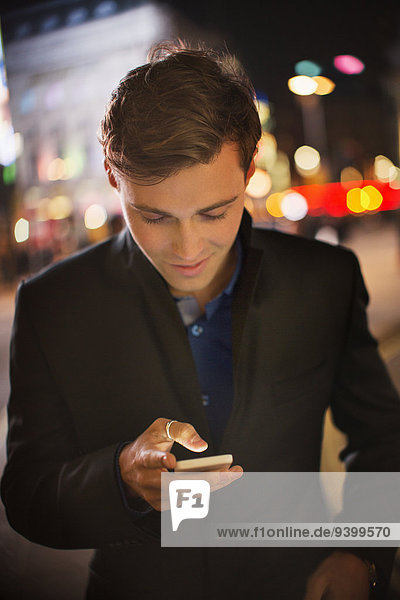 Mann mit Handy in der Stadt bei Nacht