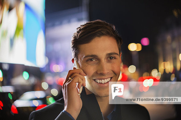 Ein Mann, der nachts auf dem Handy in der Stadt telefoniert.