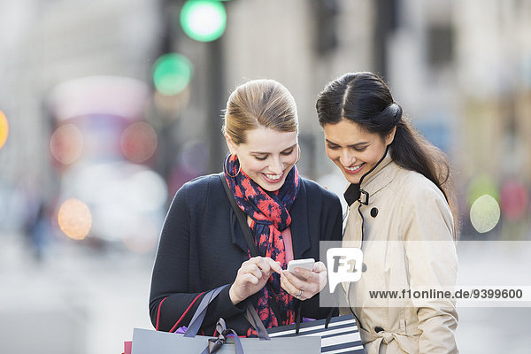 Frauen schauen auf das Handy in der Stadtstraße