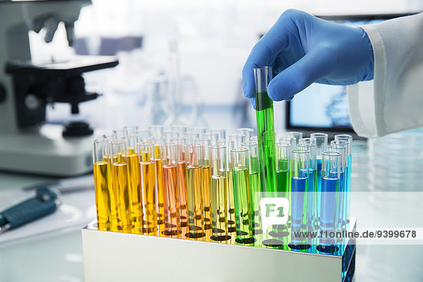 Wissenschaftler pflückt Reagenzglas aus dem Regal auf der Theke im Labor