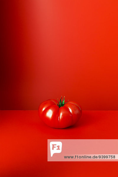 Tomate sitzend auf roter Theke