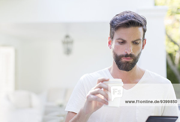 Mann trinkt Kaffee und benutzt digitale Tabletten