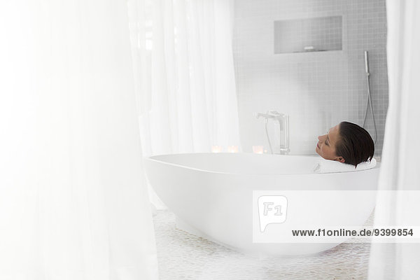 Woman relaxing in bath in modern bathroom