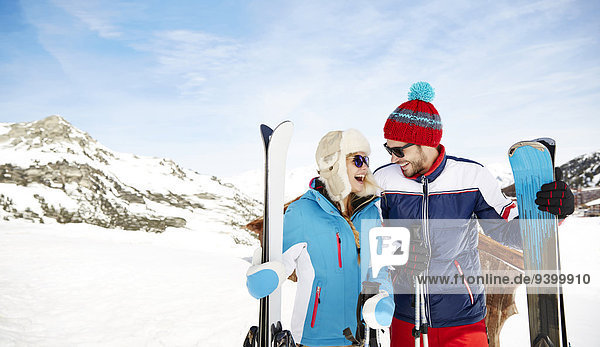 Couple holding skis together