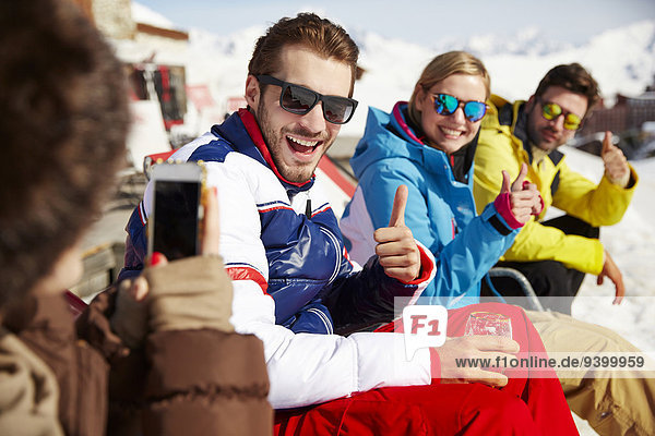 Frau beim Fotografieren von Freunden im Schnee