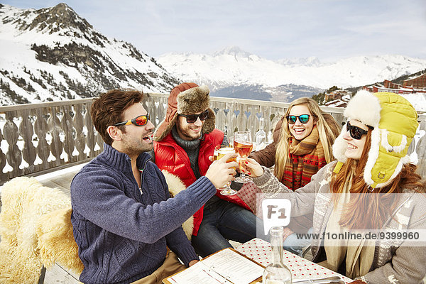 Freunde beim Feiern mit Getränken im Schnee