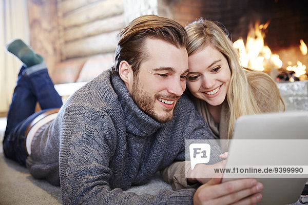 Couple using digital tablet by fireplace together