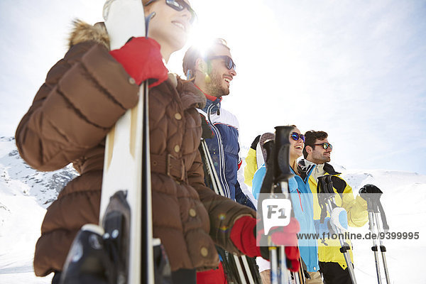 Freunde stehen mit Skiern auf dem Berggipfel