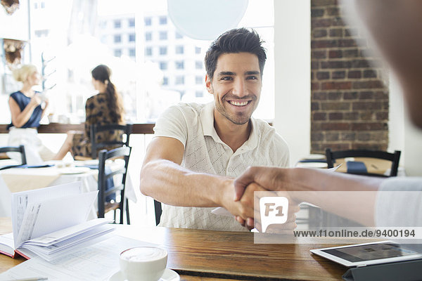 Businessmen shaking hands in cafe