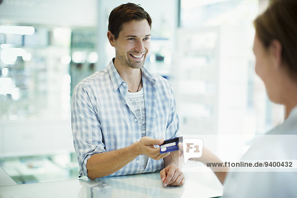 Mann bezahlt mit Kreditkarte in der Apotheke