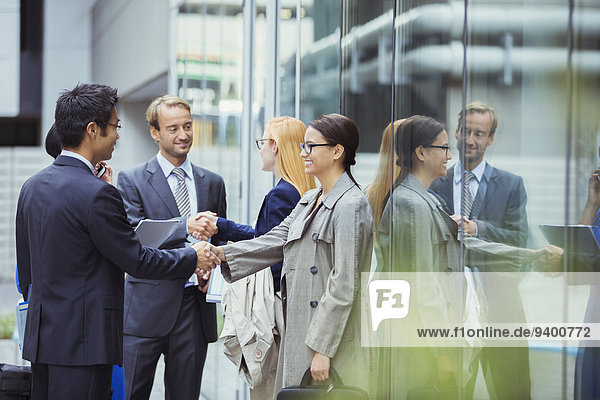 Business people shaking hands outside of office building