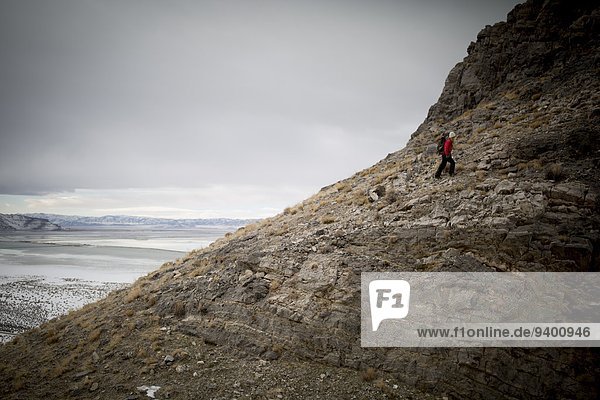 A young woman hikes high above the Great Salt Lake in the desert mountains.