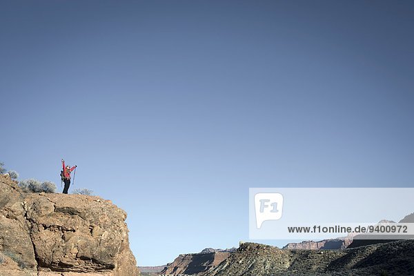 A young woman hikes the red rock of southern Utah  overlooking desert.