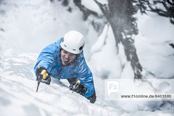Man lead climbing an ice fall in the middle of a snow storm in Simplon Pass  Valais  Switzerland.
