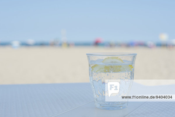 Wasserglas mit Zitronenscheibe auf einem Tisch in der Strandbar  Adria  Italien