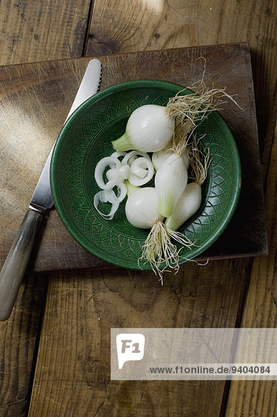 Spring onions on a plate cutting board with knife