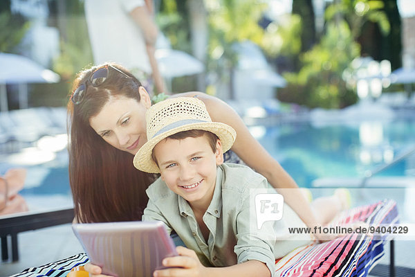 Mutter und Sohn mit Tablet PC am Schwimmbad