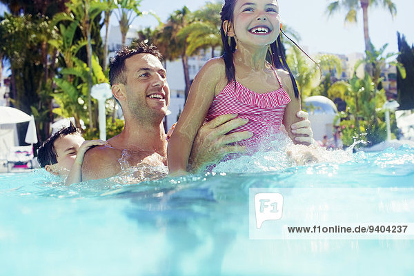 Vater mit Tochter und Sohn beim Spielen im Schwimmbad