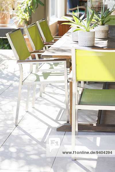 Stühle und Tisch mit Topfpflanzen auf der Terrasse