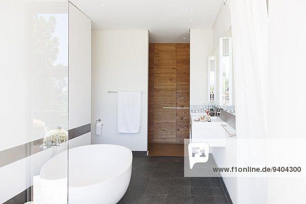 Moderne Badezimmerausstattung mit großer Badewanne und Holztür