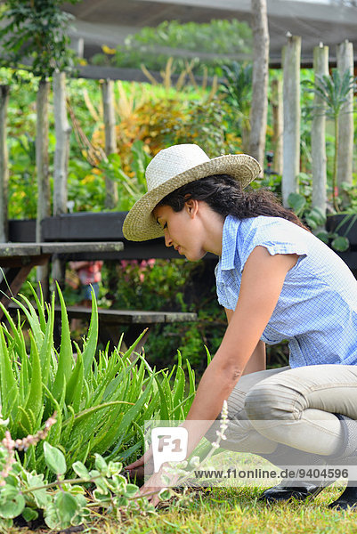 Woman wearing straw hat and rubber boots gardening in garden