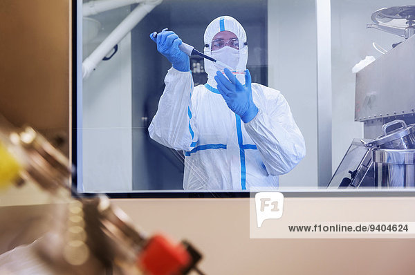 Wissenschaftler im Clean Suit Pipettieren der Probe in die Petrischale im Labor