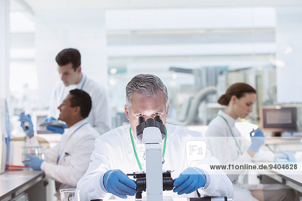 Scientist examining sample under microscope in laboratory