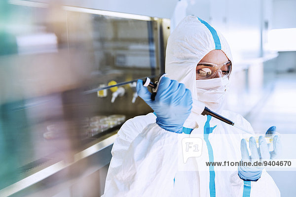 Wissenschaftler im Clean Suit Pipettieren der Probe in die Petrischale im Labor