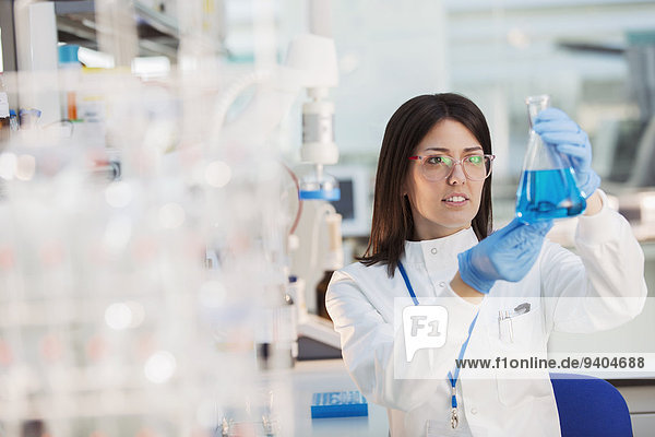 Scientist examining sample in beaker in laboratory