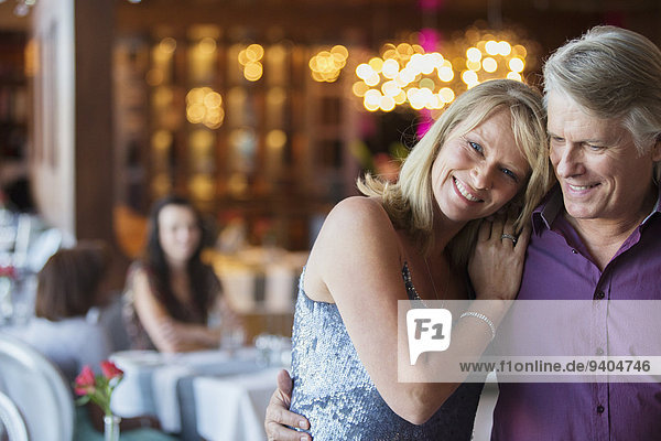 Mann umarmt Frau im Restaurant  Menschen im Hintergrund