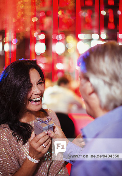 Mann schenkt lächelnde reife Frau im Nachtclub