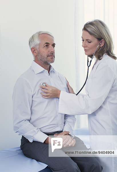 Female doctor examining her patient with stethoscope in office