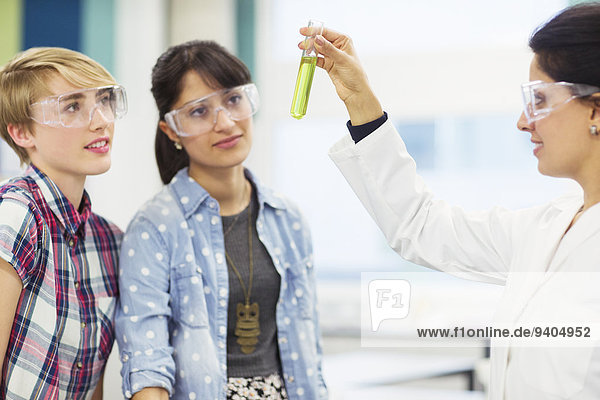 Schüler mit ihrem Lehrer im Chemielabor  Lehrer im Reagenzglas mit grüner Flüssigkeit