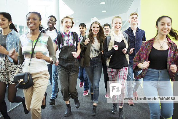 Group of cheerful students running in corridor