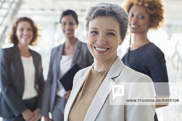 Portrait of smiling mature businesswoman with office team in background