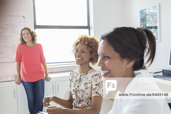 Drei Frauen lachen während des Treffens im Büro