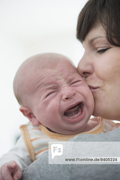 Mother holding her crying son  close up