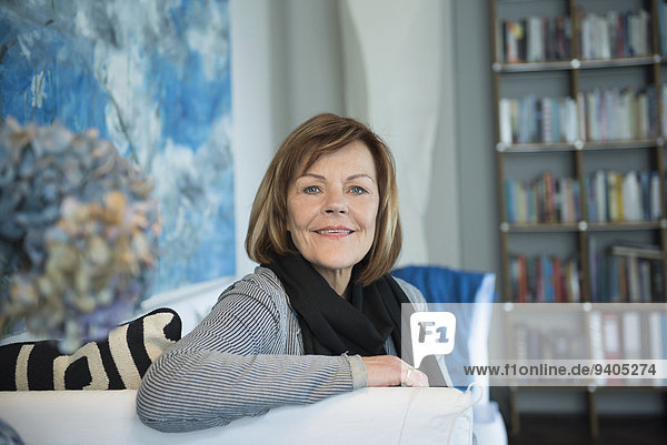 Portrait of senior woman sitting on couch in living room  smiling