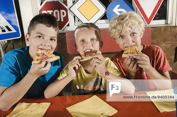 Three boys eating pizza at driver training area