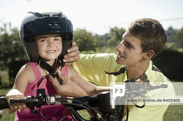 Tutor assisting girl with helmet on driver training area