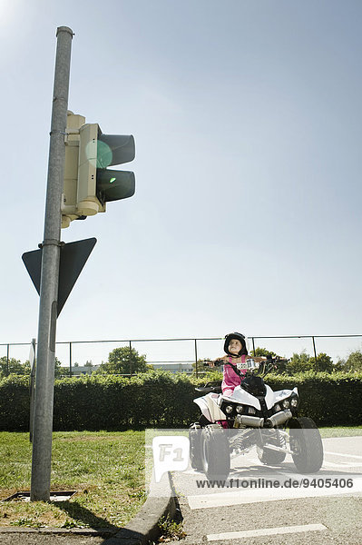 Girl with quadbike waiting at traffic light on driver training area