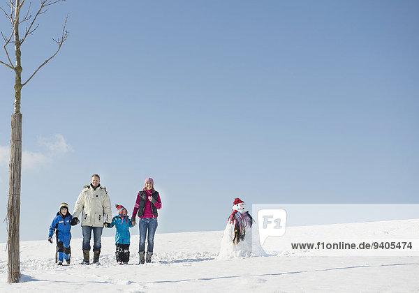 Family standing on snow near snowman