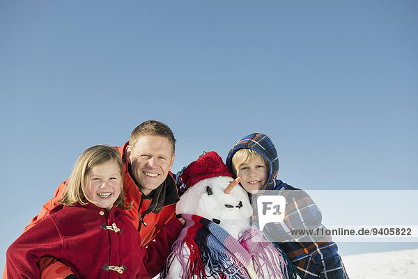 Portrait of family with snowman  smiling