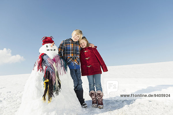 Girl and boy with snowman  smiling
