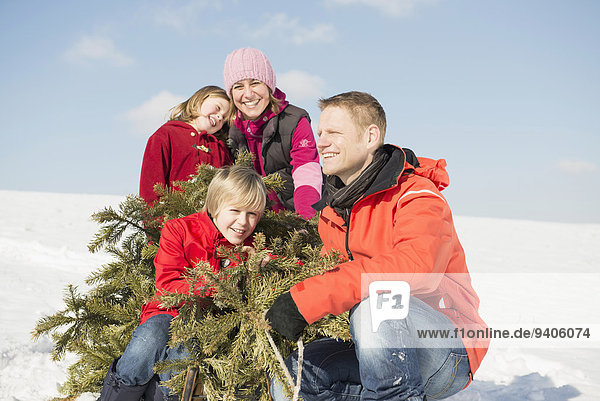 Family sitting with branches in winter  smiling