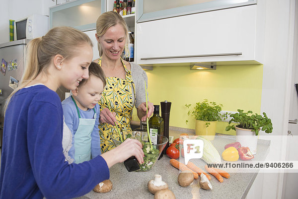 Mother and children preparing salad in kitchen  smiling