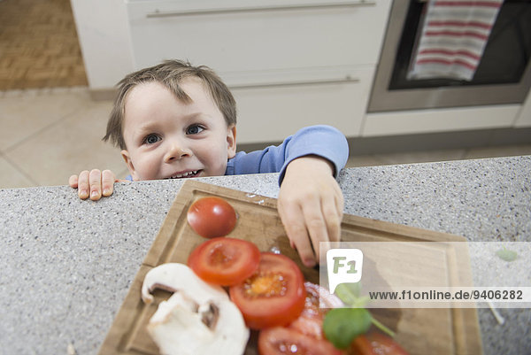 Boy looking at chopped vegetables in kitchen